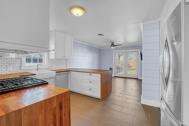 kitchen with sink, butcher block countertops, plenty of natural light, stainless steel appliances, and white cabinets