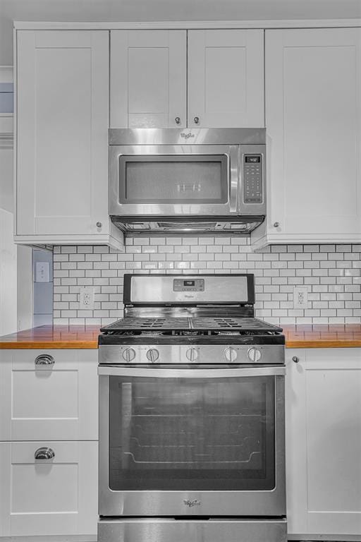 kitchen featuring stainless steel appliances, butcher block counters, white cabinets, and backsplash