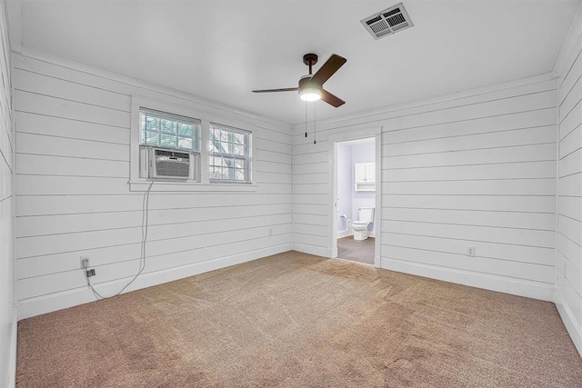 carpeted empty room featuring cooling unit, ceiling fan, and wooden walls