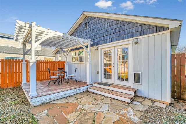 exterior space with a wooden deck, a pergola, and french doors