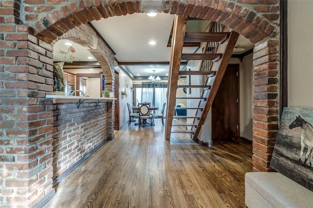 interior space featuring crown molding, brick wall, dark hardwood / wood-style floors, and a chandelier