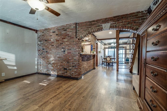 interior space featuring hardwood / wood-style flooring, a textured ceiling, and brick wall