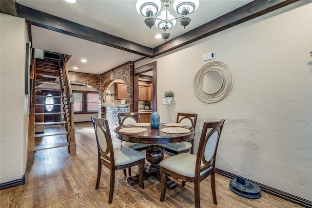 dining area featuring beam ceiling, a notable chandelier, and hardwood / wood-style flooring