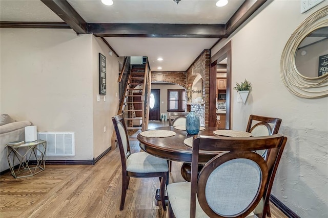 dining room featuring beam ceiling and light hardwood / wood-style floors