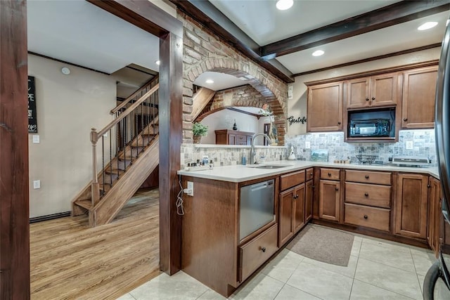 kitchen featuring black microwave, dishwasher, sink, kitchen peninsula, and beam ceiling