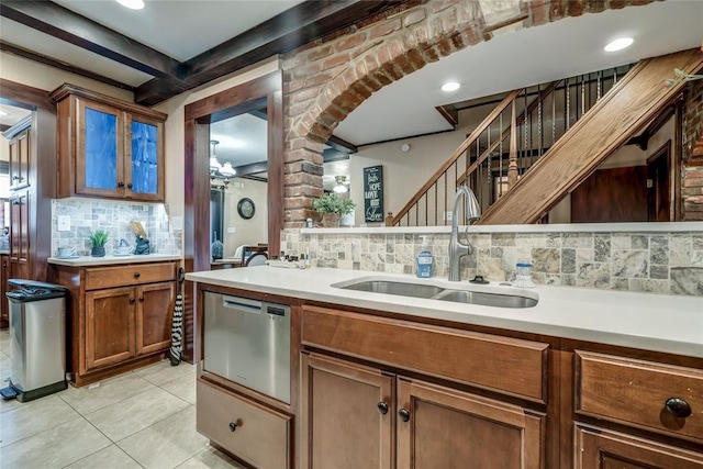 kitchen with sink, light tile patterned flooring, decorative backsplash, stainless steel dishwasher, and beamed ceiling