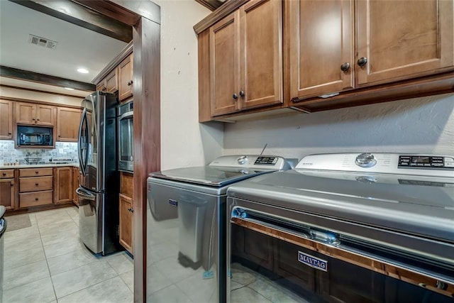 laundry room with cabinets, light tile patterned floors, and washing machine and clothes dryer