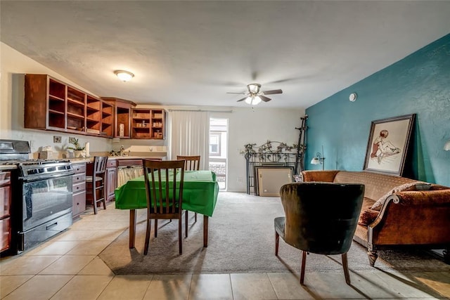 kitchen featuring light colored carpet, gas stove, and ceiling fan