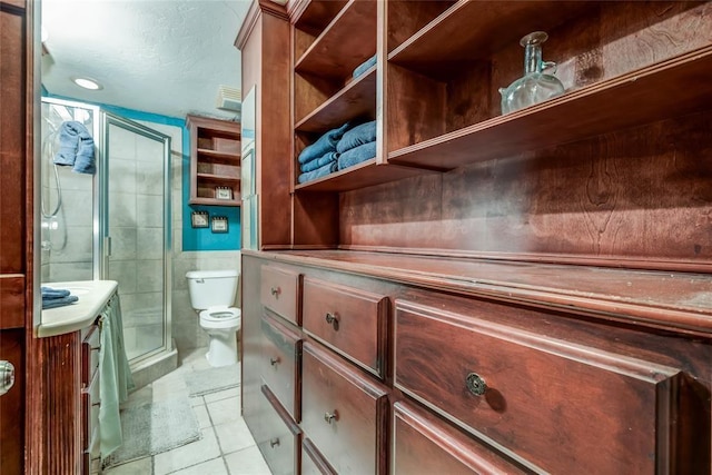 bathroom with vanity, toilet, a shower with shower door, and tile patterned flooring