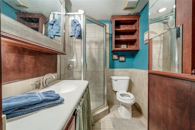 bathroom featuring tile walls, vanity, an enclosed shower, toilet, and tile patterned floors