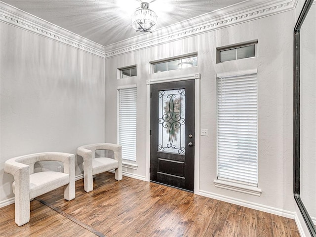 entrance foyer featuring crown molding, hardwood / wood-style flooring, and a chandelier