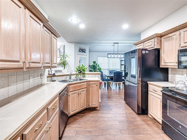 kitchen with pendant lighting, sink, dark hardwood / wood-style flooring, black appliances, and light brown cabinets