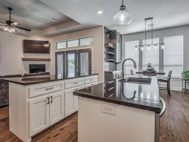 kitchen with decorative light fixtures, sink, and a center island with sink