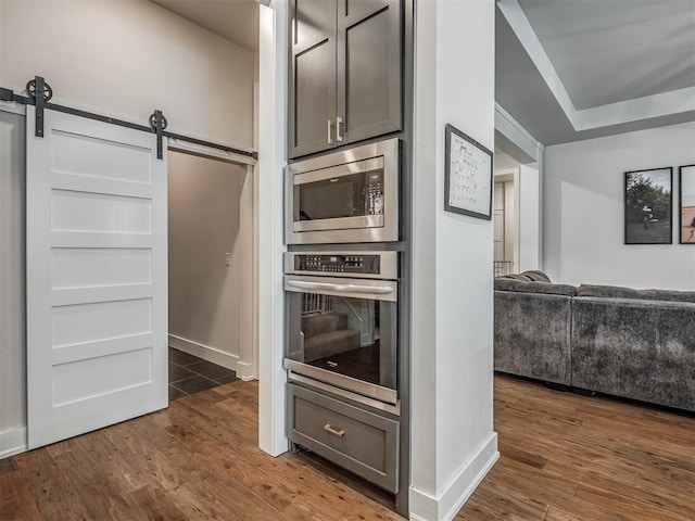 kitchen featuring dark hardwood / wood-style floors, stainless steel appliances, and a barn door