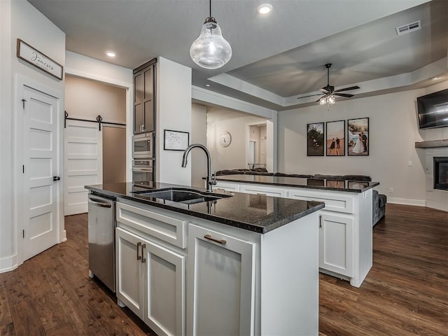 kitchen featuring sink, white cabinets, a kitchen island with sink, a raised ceiling, and a barn door