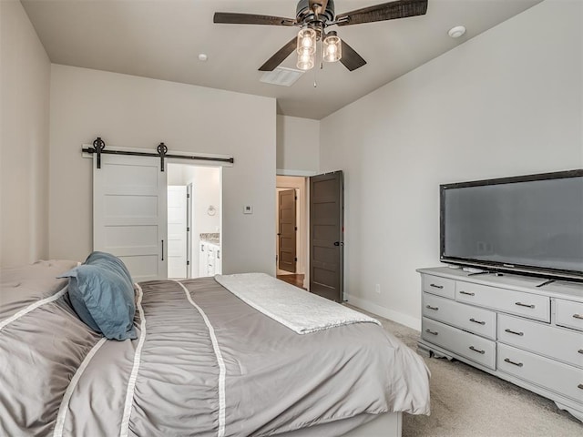 bedroom with ceiling fan, connected bathroom, a barn door, and light carpet