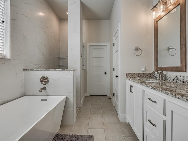 bathroom with a washtub, vanity, and tile patterned flooring