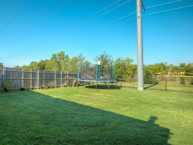 view of yard with a trampoline and a fenced backyard