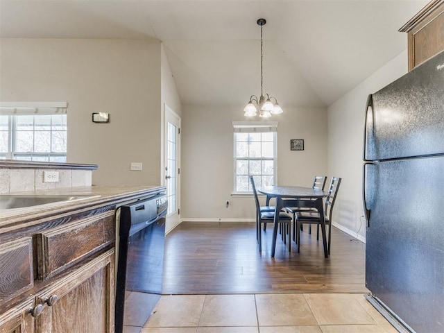 tiled dining space with lofted ceiling and a notable chandelier