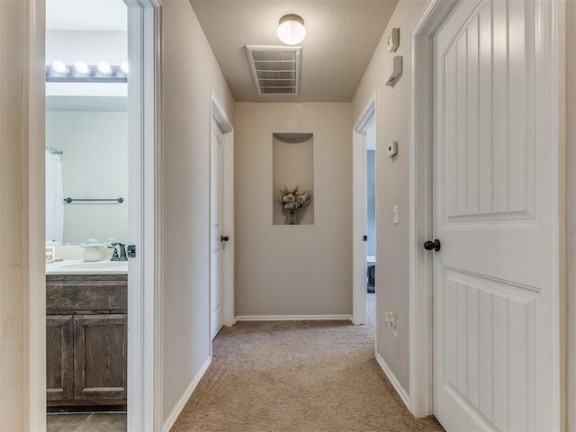 hallway with sink and light carpet