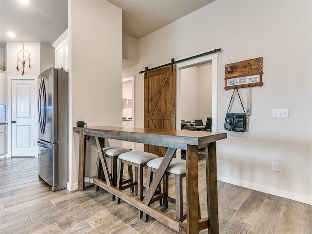 kitchen with white cabinetry, a barn door, and stainless steel refrigerator