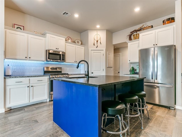 kitchen featuring white cabinetry, appliances with stainless steel finishes, sink, and a center island with sink