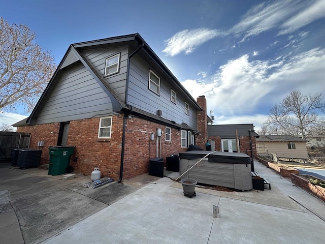 rear view of house with a hot tub, a patio, and central air condition unit