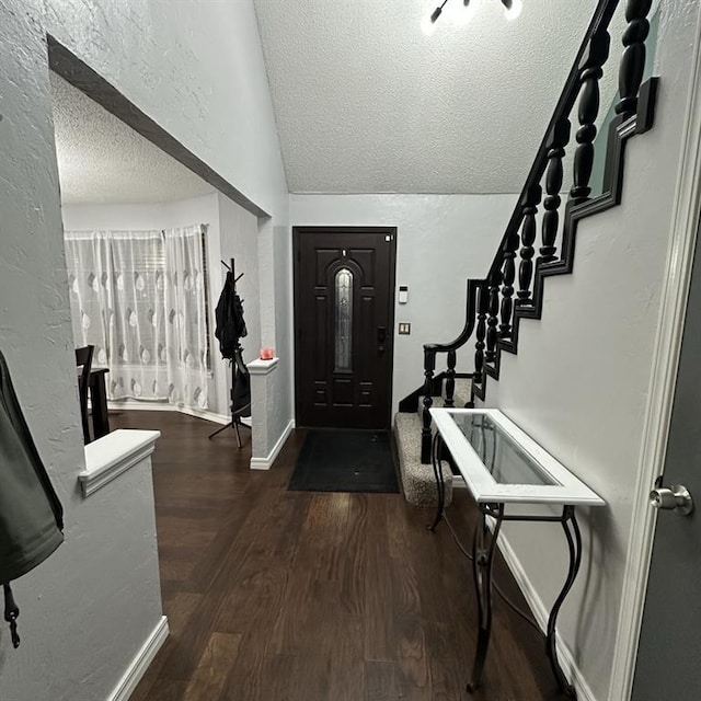 foyer entrance with vaulted ceiling, dark hardwood / wood-style floors, and a textured ceiling