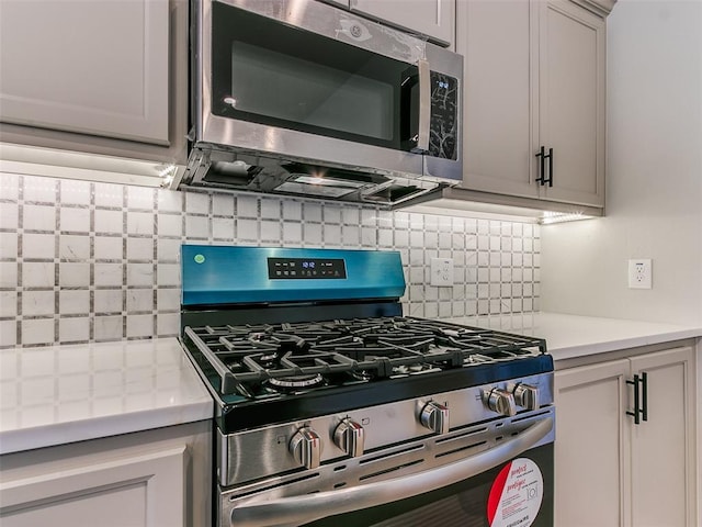 kitchen featuring stainless steel appliances, gray cabinets, and decorative backsplash