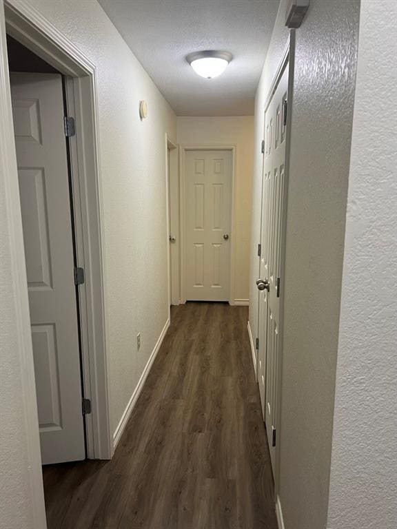 hall with dark wood-type flooring and a textured ceiling