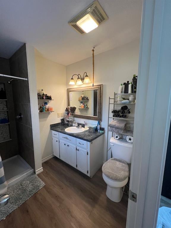 bathroom featuring walk in shower, wood-type flooring, toilet, and vanity