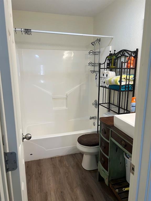 full bathroom with shower / washtub combination, toilet, hardwood / wood-style floors, and vanity