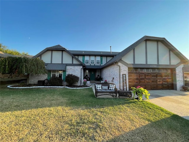 tudor home featuring a garage and a front lawn