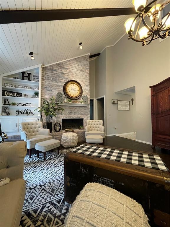 living room featuring a large fireplace, a notable chandelier, and wood ceiling