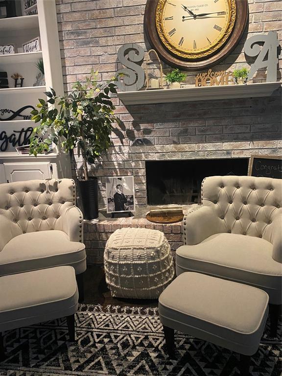 living area with brick wall and a fireplace