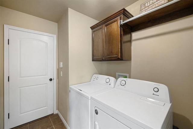 clothes washing area with dark tile patterned flooring, washer and clothes dryer, and cabinets