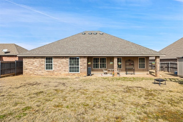 rear view of property featuring a yard, a patio area, and an outdoor fire pit