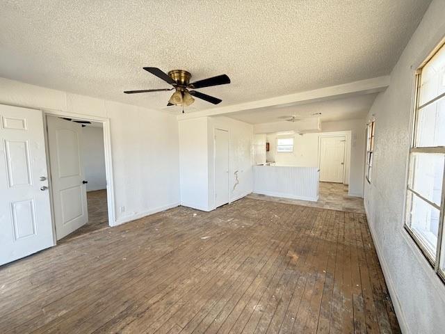 unfurnished living room featuring hardwood / wood-style flooring, ceiling fan, and a textured ceiling