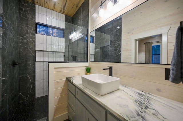 bathroom featuring wood ceiling, vanity, tile walls, and a tile shower