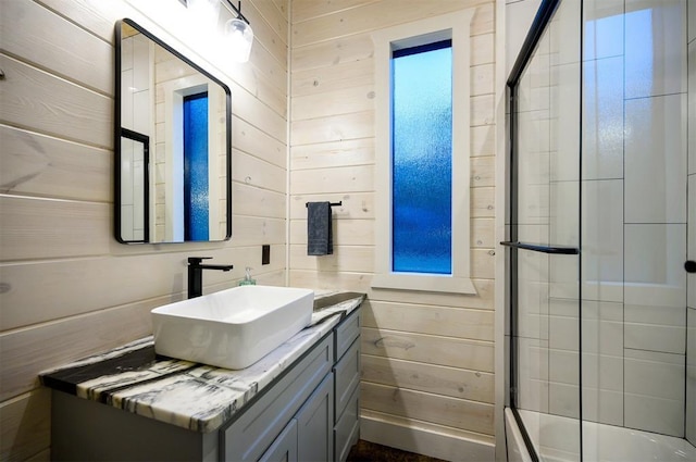 bathroom with vanity, an enclosed shower, and wooden walls