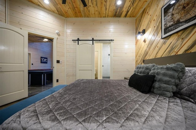 bedroom with wooden walls, wooden ceiling, and a barn door