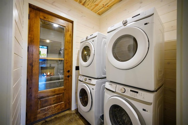 clothes washing area featuring stacked washer and clothes dryer and wooden walls