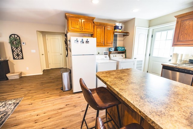 kitchen with light hardwood / wood-style flooring, a breakfast bar, dishwasher, independent washer and dryer, and white refrigerator