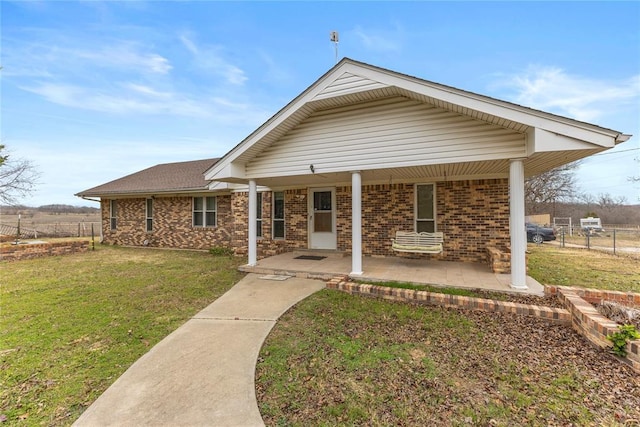 view of front of house with brick siding, a front lawn, fence, and roof with shingles