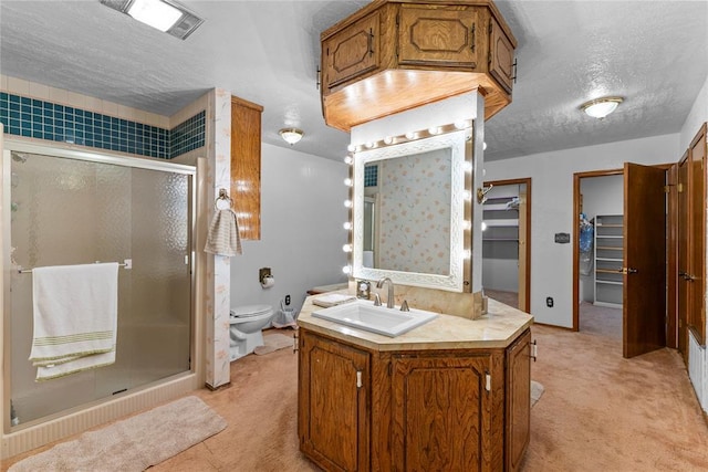 full bathroom featuring vanity, a textured ceiling, toilet, a shower stall, and a walk in closet