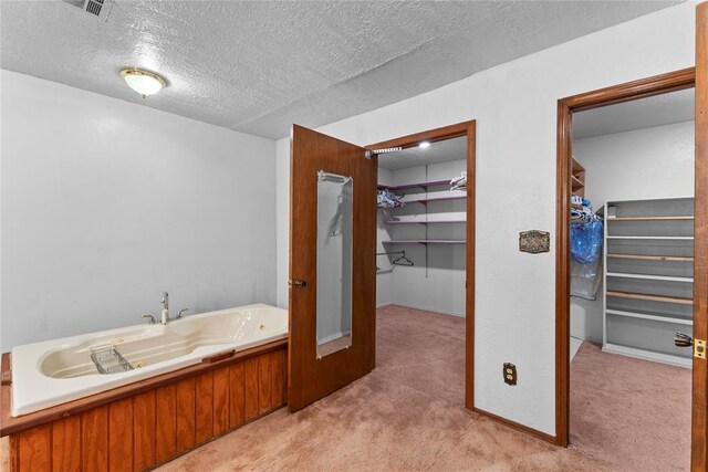 bathroom with a spacious closet, a bath, and a textured ceiling