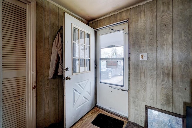 doorway with light hardwood / wood-style flooring and wood walls