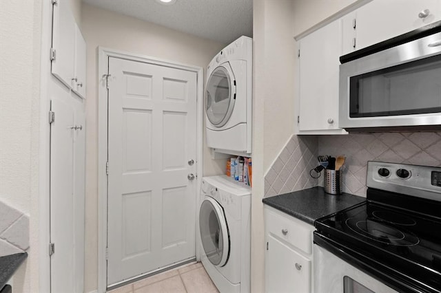 washroom with light tile patterned flooring and stacked washing maching and dryer