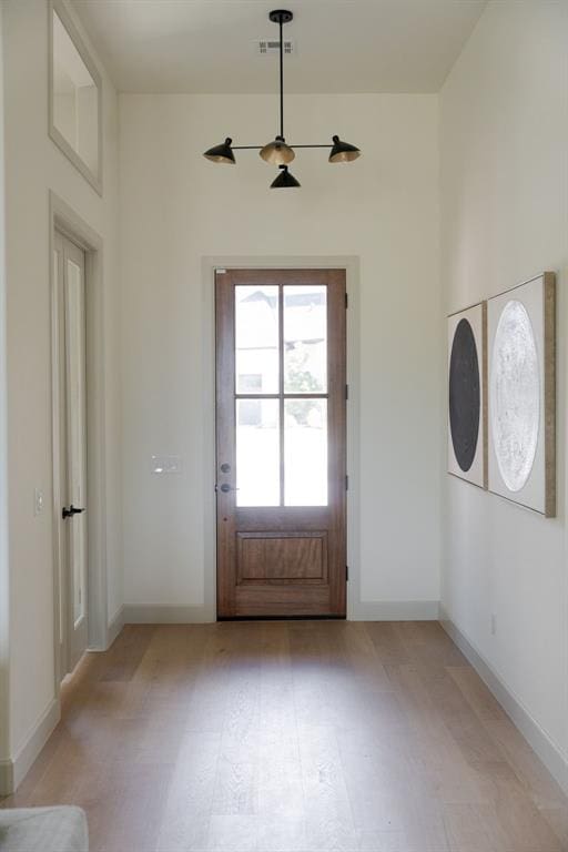 doorway with light floors, baseboards, and visible vents