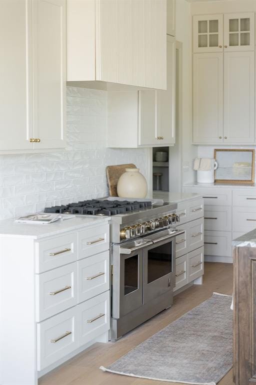 kitchen with light countertops, white cabinets, double oven range, and decorative backsplash